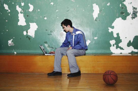 Man working on laptop with basketball at the side
