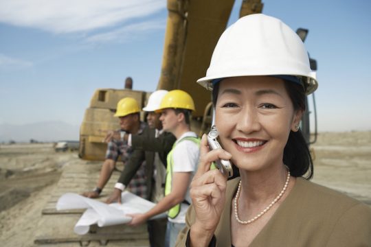 Woman Surveyor Using Cell Phone on Construction Site